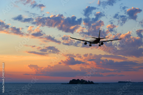 Airplane flying over the sea at sunset