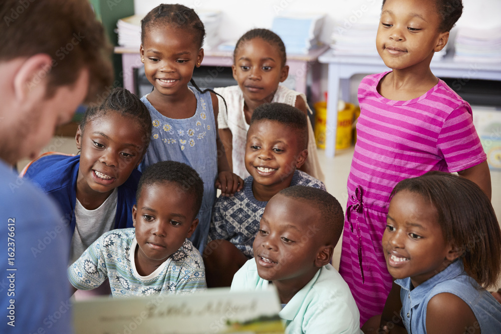 Teacher reading book to elementary school children in class Teacher reading book to elementary school children in class