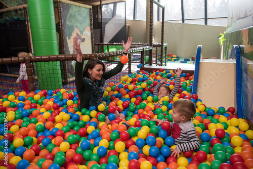 Young mom with her kids in a children's playroom photo