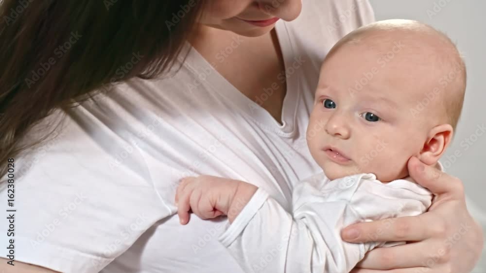 Tilt up of affectionate mother holding lovely baby boy on arms Tilt up of affectionate mother holding lovely baby boy on arms