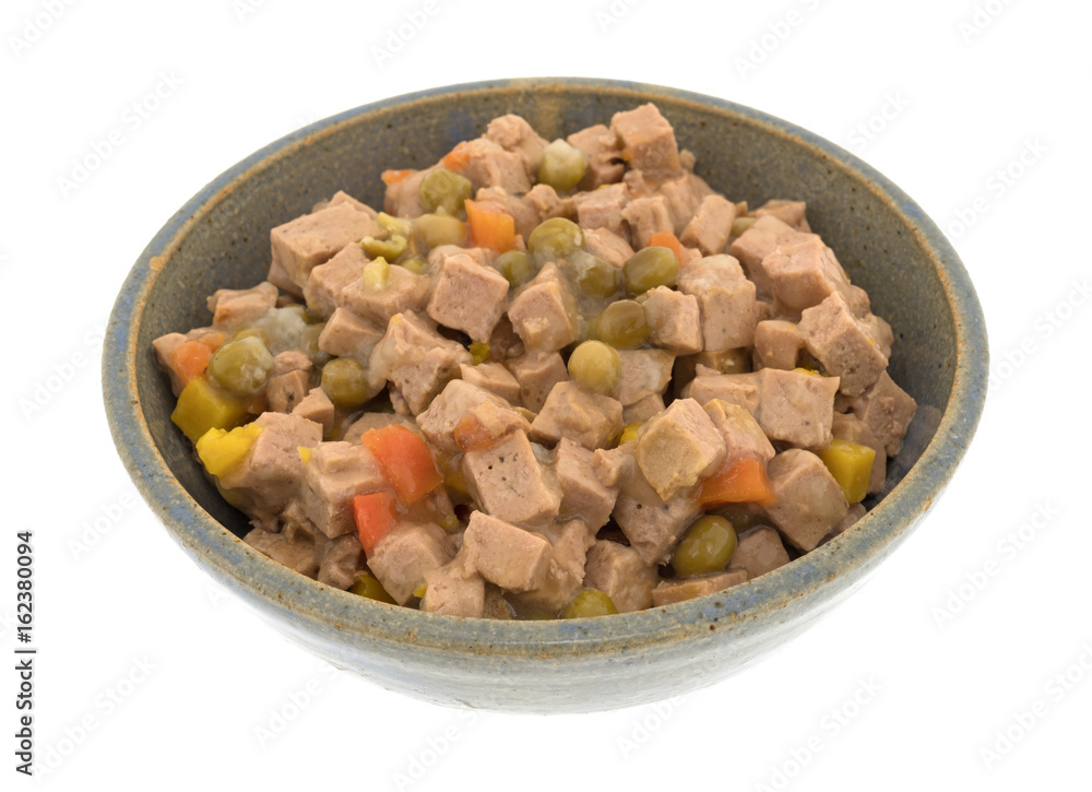 An old stoneware bowl filled with lamb dog food isolated on a white background. An old stoneware bowl filled with lamb dog food isolated on a white background.