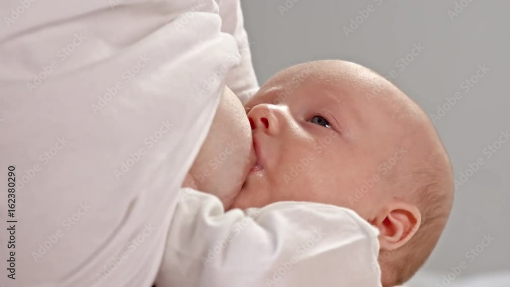 Closeup of little baby boy eating milk from breast of his mother Closeup of little baby boy eating milk from breast of his mother