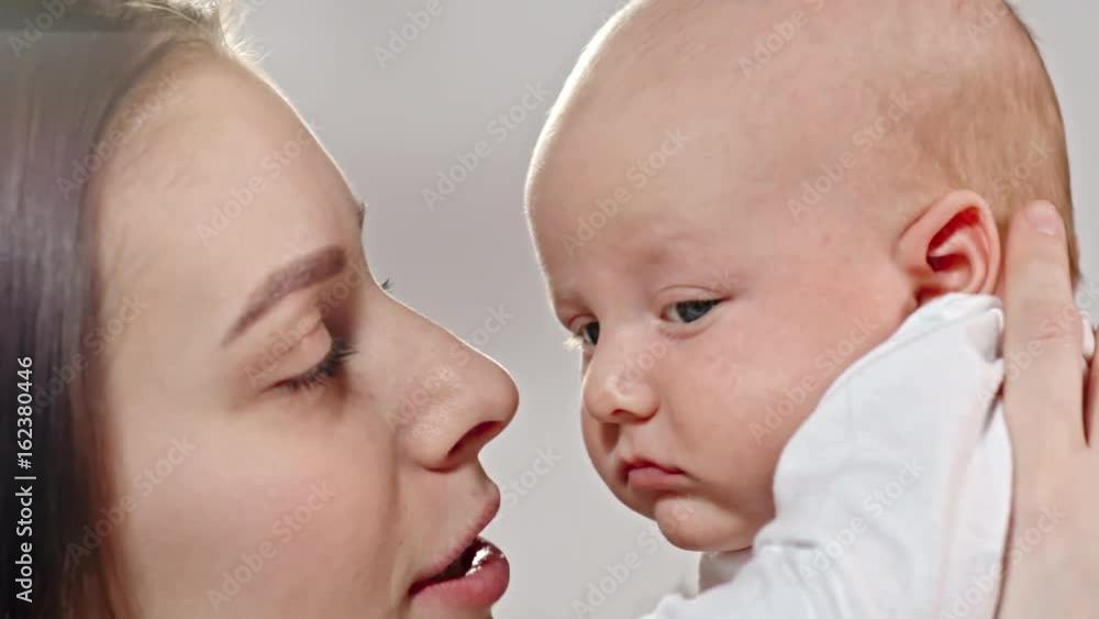 Slow motion of young mother lifting up her baby and tenderly kissing him Slow motion of young mother lifting up her baby and tenderly kissing him
