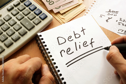 Obraz na plátne Note with words debt relief on a table.