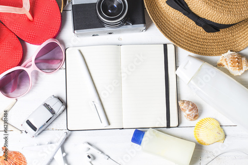 Beach accessories. Bag, towel, sunglasses and flip-flops on wooden background. Top view with copy space