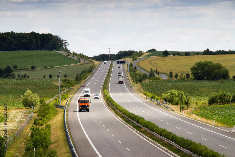 Highway transportation with cars and truck. Motorway in countryside. View from above.