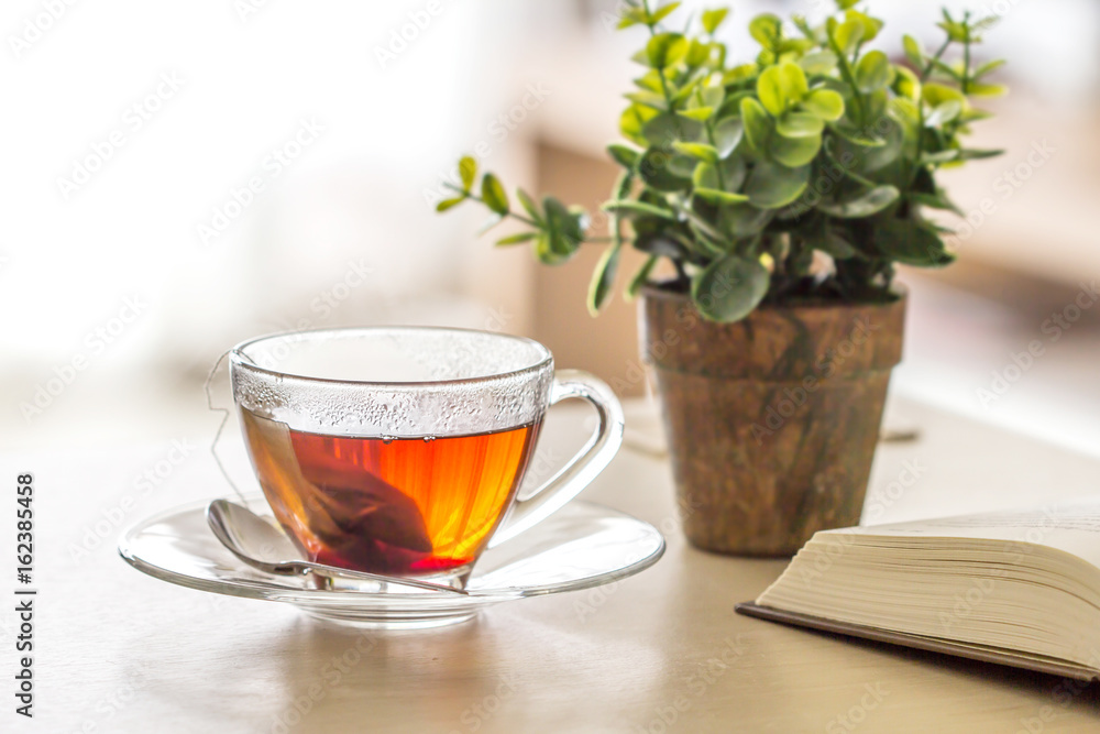 Close up the warm black tea cup on the wooden table in living room , relax with tea time concept Close up the warm black tea cup on the wooden table in living room , relax with tea time concept
