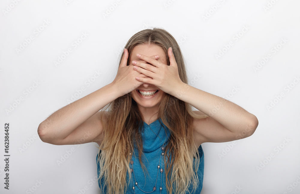Headshot of young adorable blonde woman with cute smile on white background covers her face with palms Headshot of young adorable blonde woman with cute smile on white background covers her face with palms