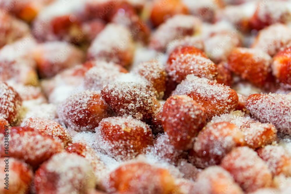 Close up of strawberries sprinkled with sugar, preparation for making jam. Shallow depth of focus. Concept of home coziness Close up of strawberries sprinkled with sugar, preparation for making jam. Shallow depth of focus. Concept of home coziness