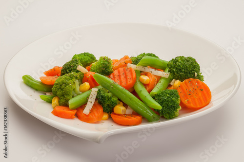 Vegetable mix with carrot, broccoli, onion, green beans and corn. On white plate