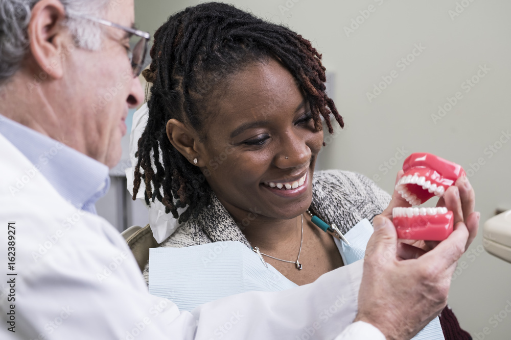 Foto de Dentist showing patient how to clean teeth during her exam do