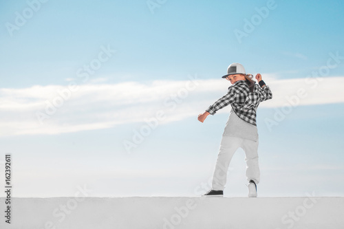 Fashion child dancing over sky background.