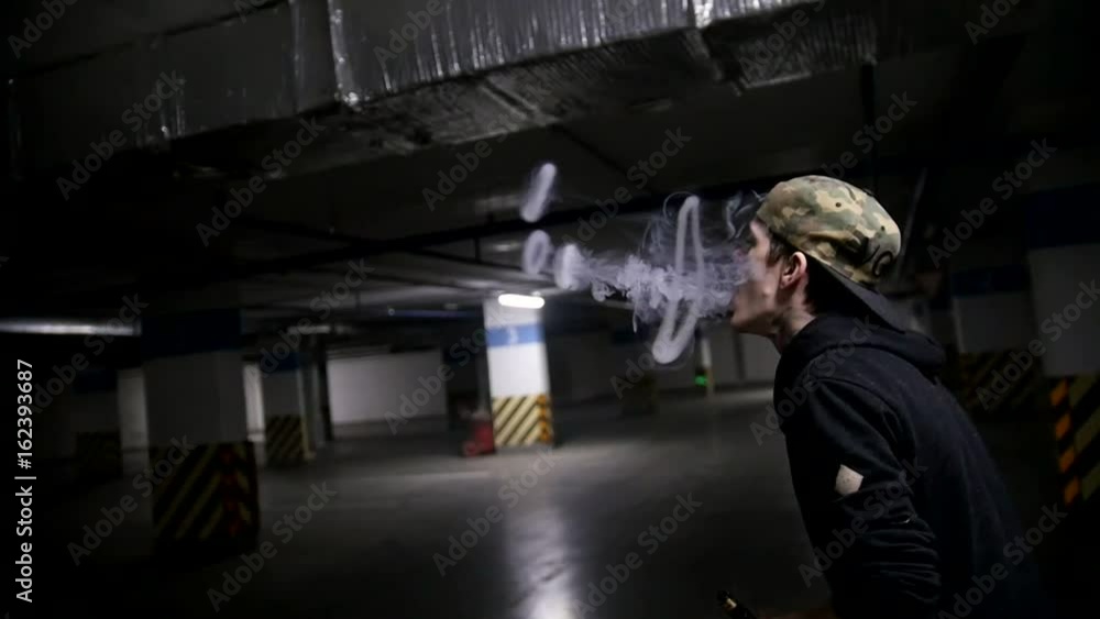 In the parking lot. The guy blows smoke from his mouth through the rings of smoke In the parking lot. The guy blows smoke from his mouth through the rings of smoke