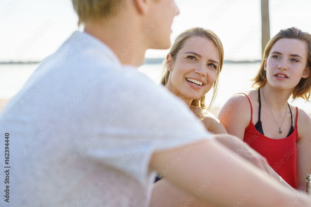 Fototapeta premium Two young women listening to a male friend