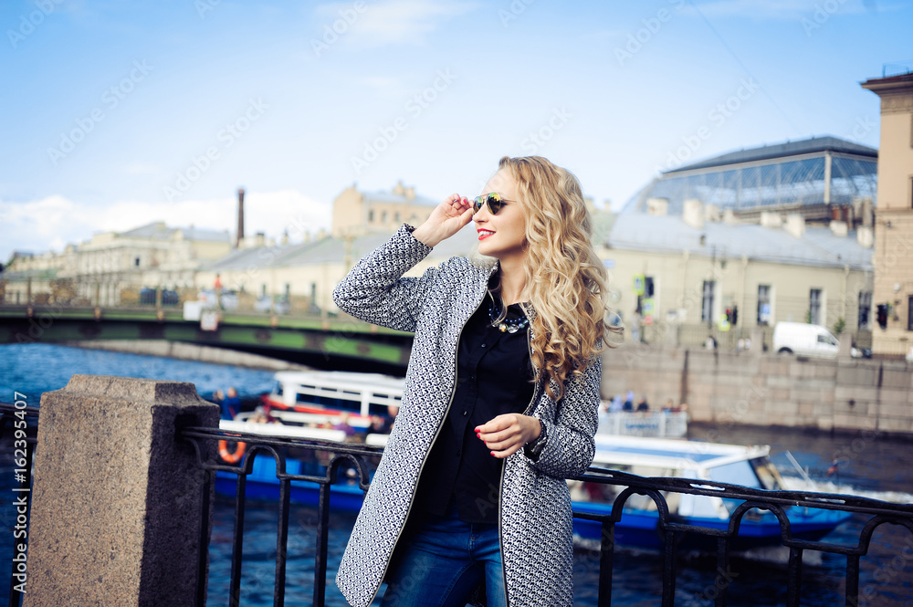 close-up portrait of a young girl hipster beautiful blonde in sunglasses with red lips laughing and posing against the backdrop of the city lifestyle