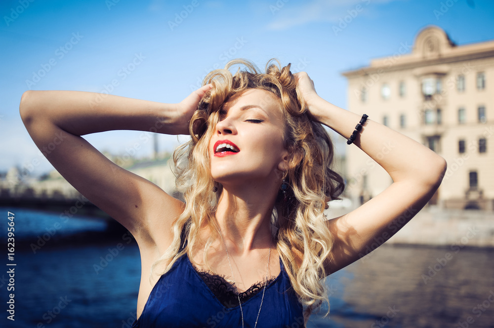 close-up portrait of a young girl hipster beautiful blonde with red lips laughing and posing against the backdrop of the city