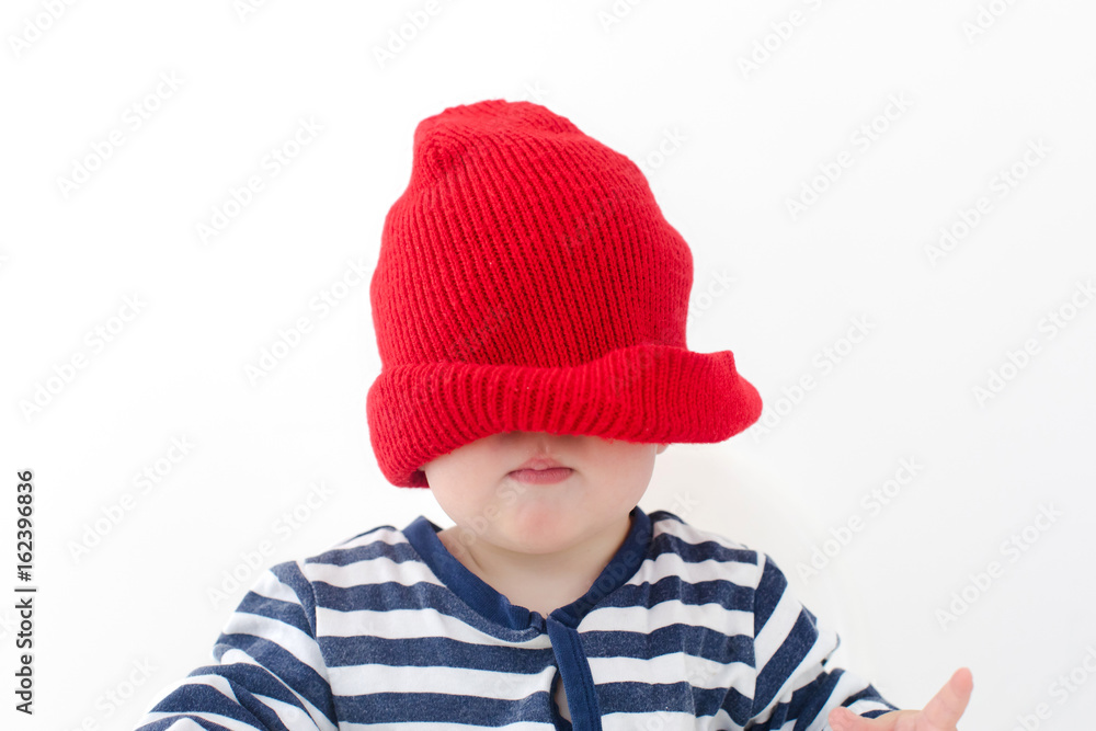 Baby in a red hat pulled over his face studio Baby in a red hat pulled over his face studio