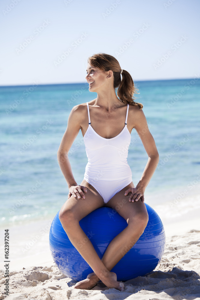 femme souriant avec une balle de gymnastique sur la plage femme souriant avec une balle de gymnastique sur la plage