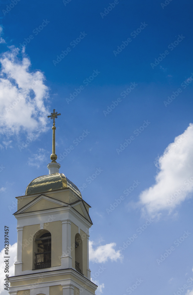 Temple of Orthodox Christians with a gold cupola against a blue sky with white clouds.