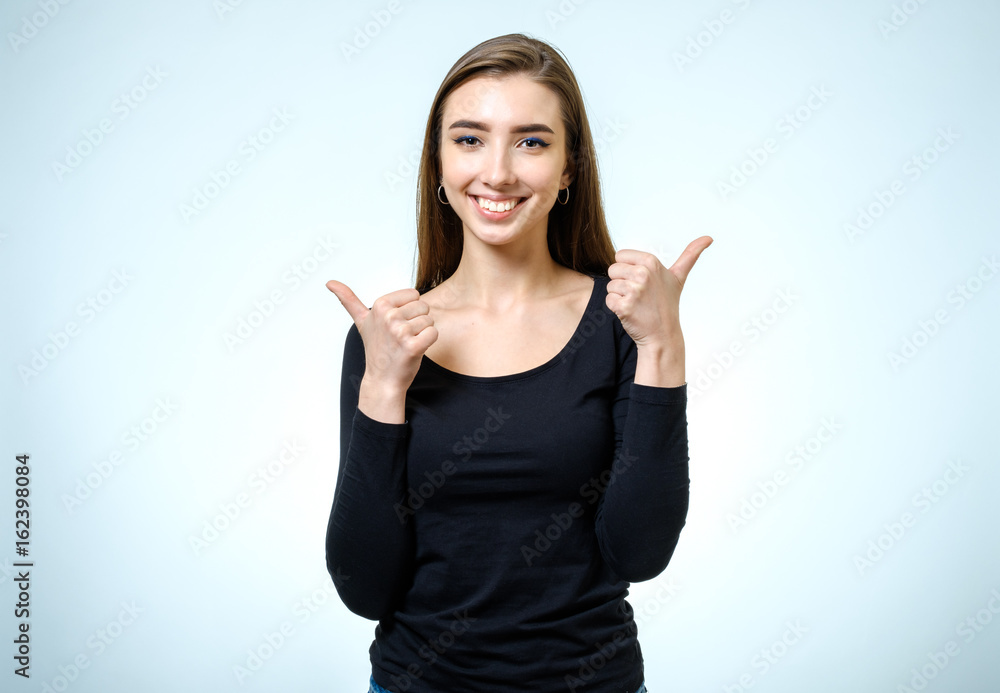 Smiling happy young brunette woman showing thumbs up gesture Smiling happy young brunette woman showing thumbs up gesture