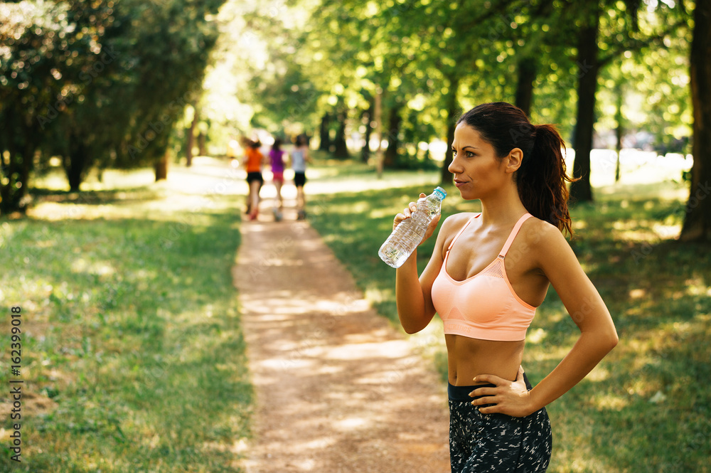 Slim young woman drinking water after training Slim young woman drinking water after training