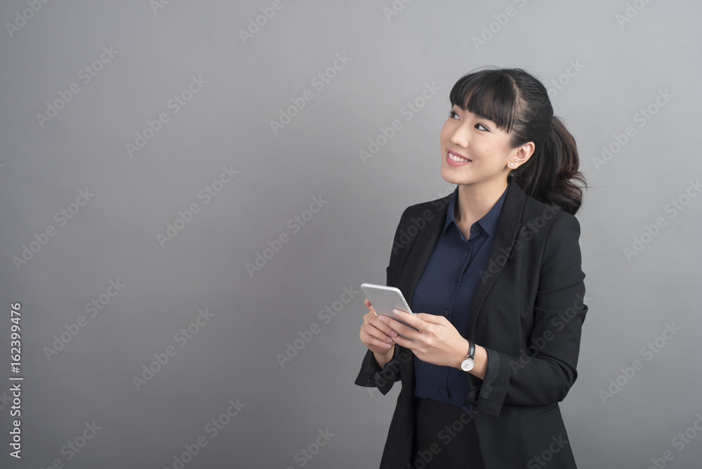Beautiful business Woman using smartphone on grey background Beautiful business Woman using smartphone on grey background