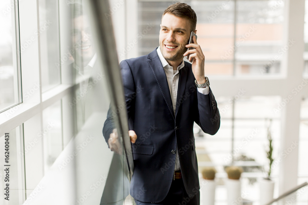 Handsome businessman talking on mobile phone while standing on the stairs Handsome businessman talking on mobile phone while standing on the stairs