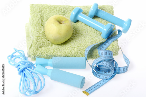 Dumbbells and cyan skipping rope, green towel with juicy apple