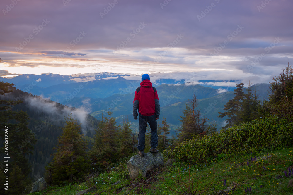 Man traveler admires a colorful sunset in the mountains
