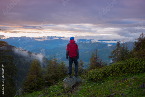 Man traveler admires a colorful sunset in the mountains