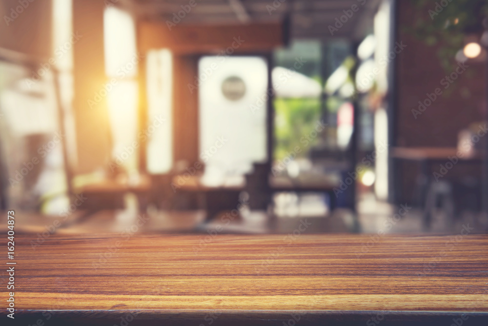 Wooden table in front of abstract blurred restaurant lights background.