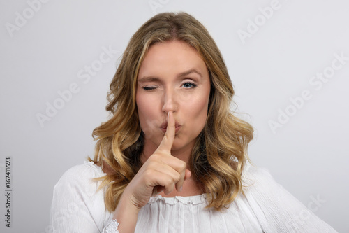 Blonde Frau mit Finger auf den Lippen