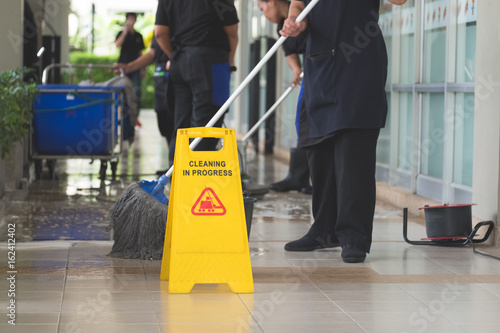 Cropped image of woman in protective gloves using a flat wet-mop and machine while cleaning floor