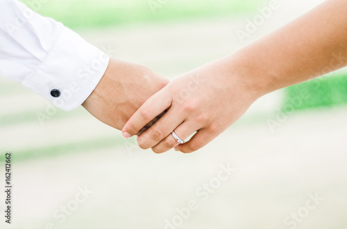 Abstract background of lovers couple holding hands with wedding ring on nature background.