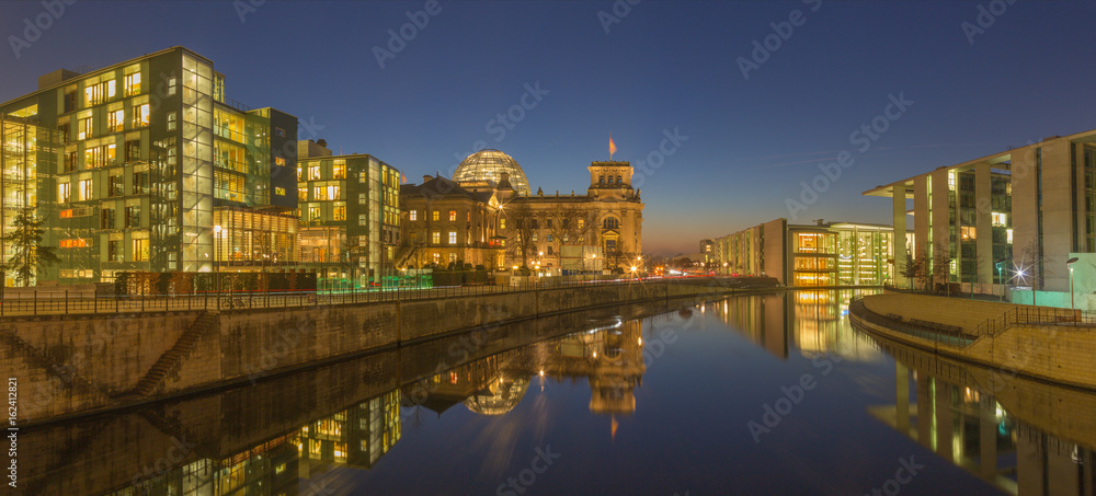 BERLIN, GERMANY, FEBRUARY - 16, 2017: Panorama of modern Government buildings and Reichstag over the Spree river in evening dusk.