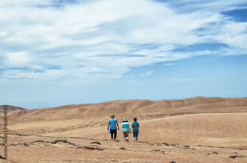 three friends walking in the desert - back view