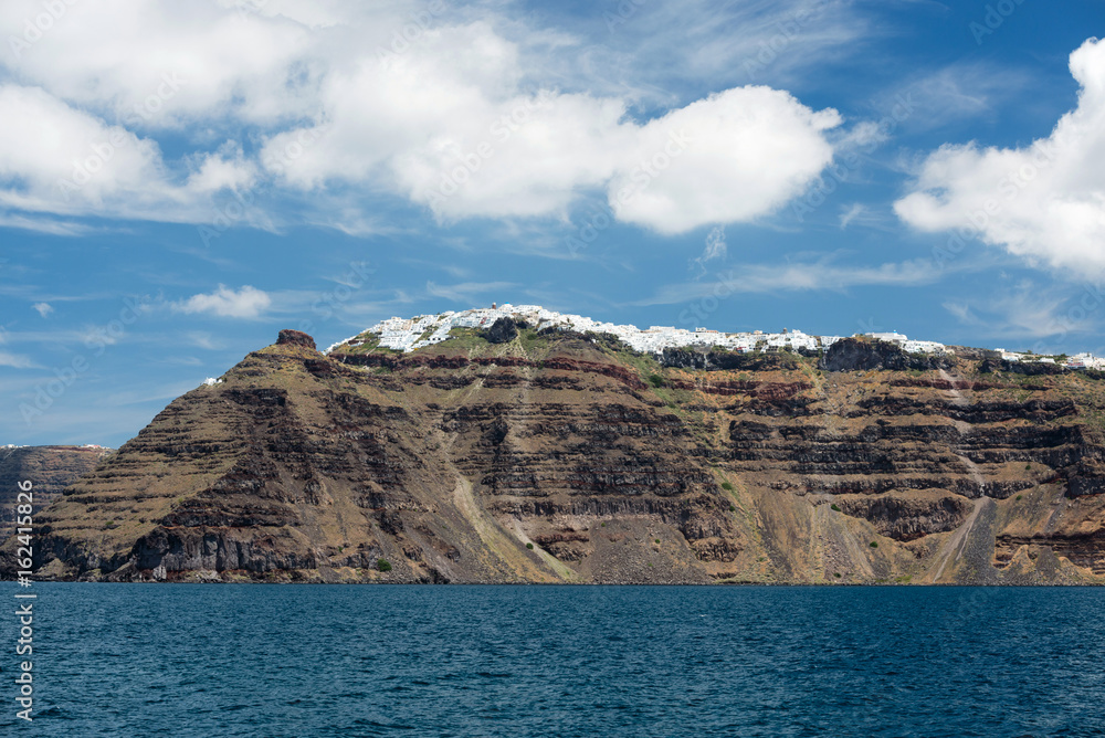 Skaros rock in front and Imerovigli village on Santorini island seen from the Aegean sea, Greece