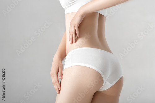 woman's ass in white lingerie on grey background