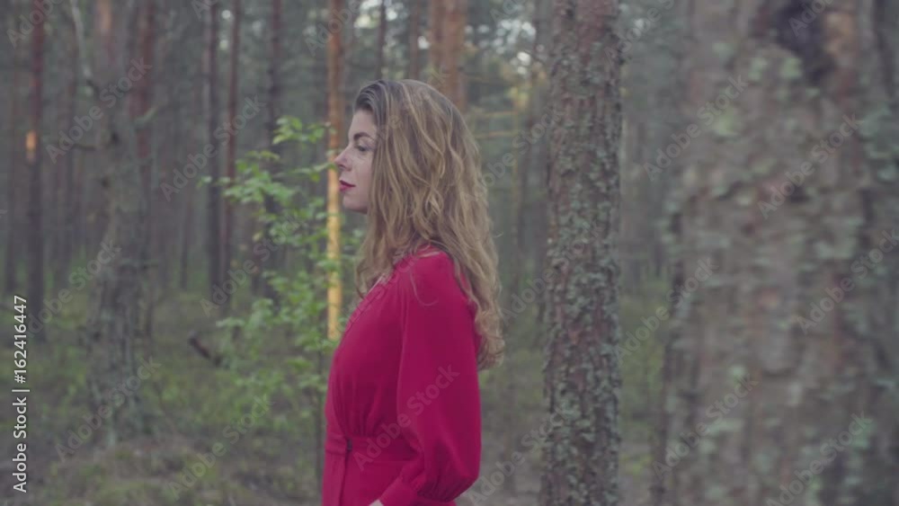 Young woman in red dress walking in the forest Young woman in red dress walking in the forest