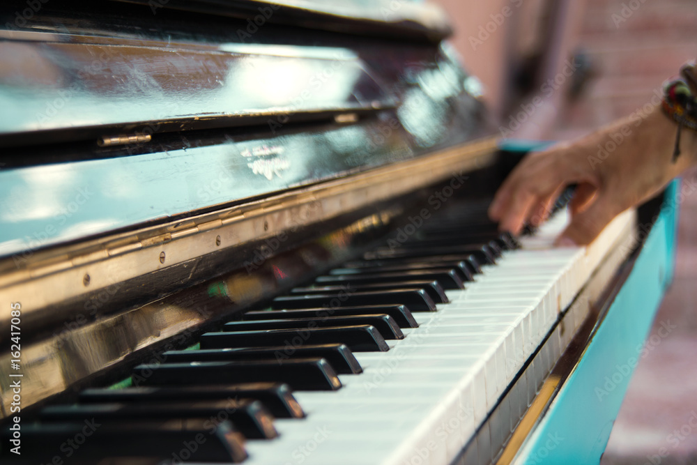 A hand of a young man playing piano on a street of city, closeup. A hand of a young man playing piano on a street of city, closeup.
