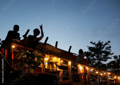 Silhouettes of people having fun on the rooftop of an outdoor club in late evening