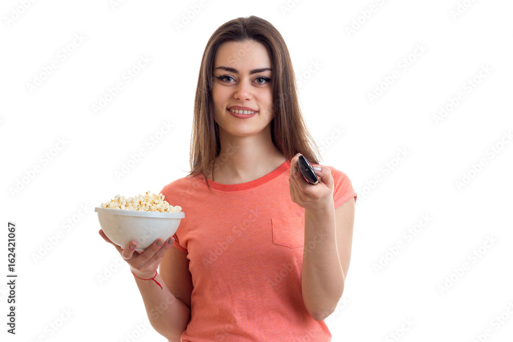 charming young girl smiling and holding a pop-corn and the remote from the tv charming young girl smiling and holding a pop-corn and the remote from the tv