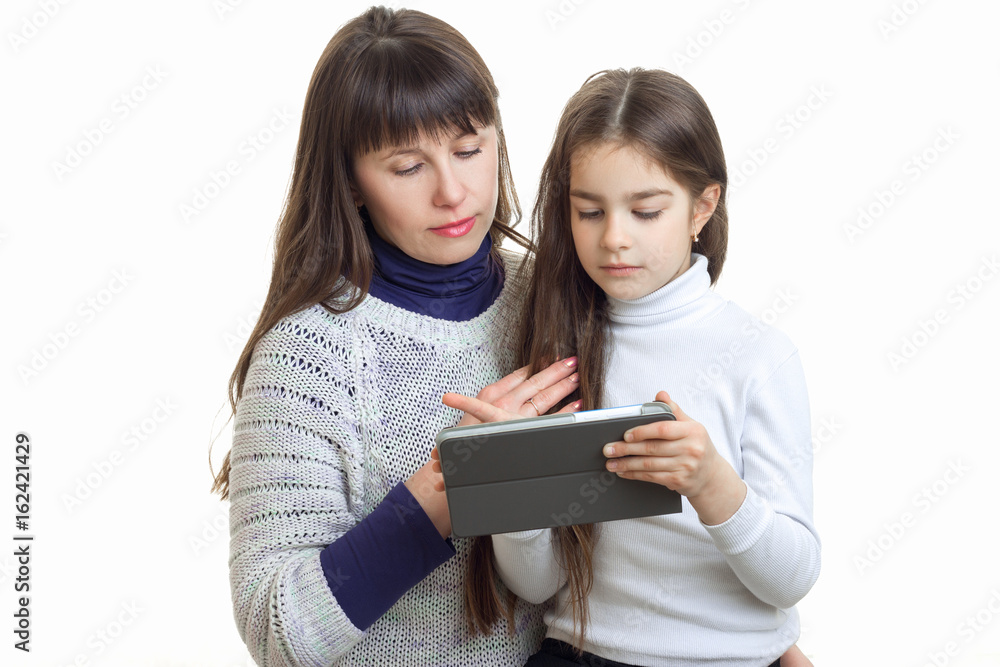 young mother and her daughter sit together and look at the Tablet is isolated on a white background young mother and her daughter sit together and look at the Tablet is isolated on a white background