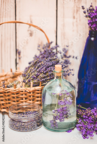 Lavender oil with fresh flowers on wooden background.