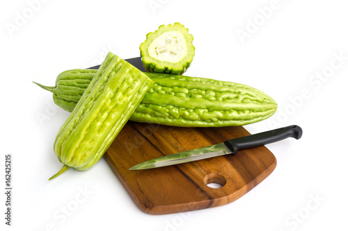 Fresh green bitter cucumber or chinese bitter melon on wooden plate isolated on white background photo