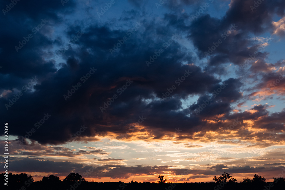 Obraz premium Warm orange sky and cold blue clouds