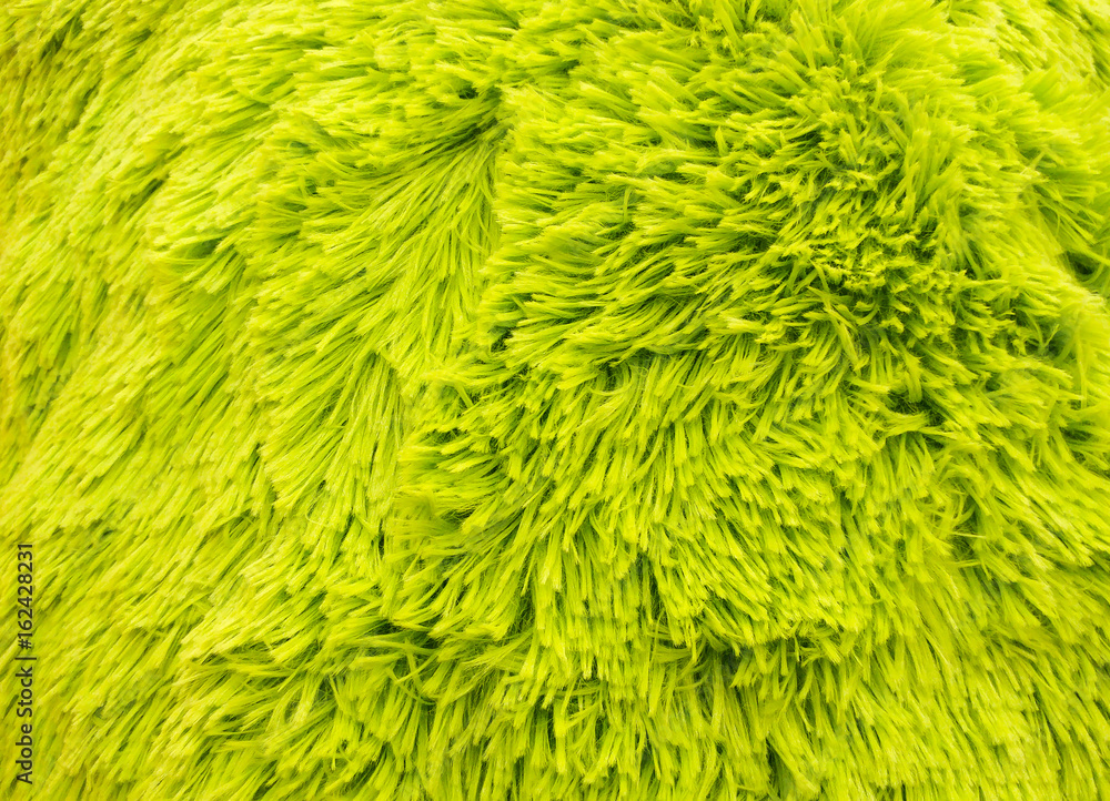 Fototapeta premium Fluffy texture fabric. Closeup of the pillow with green fur cover. Abstract background.