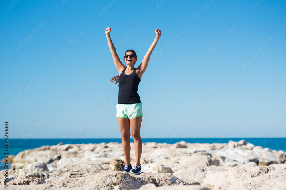 Young happy woman rising hands in victory gesture