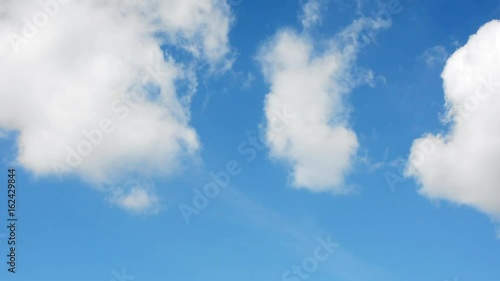 Clouds slowly moving, blue sky background