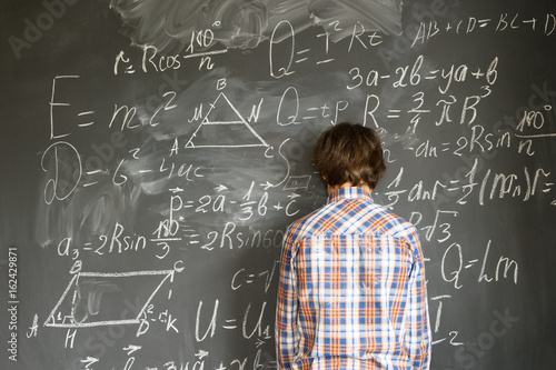 Teenageer Boy having trouble with complicated math formulas on black board